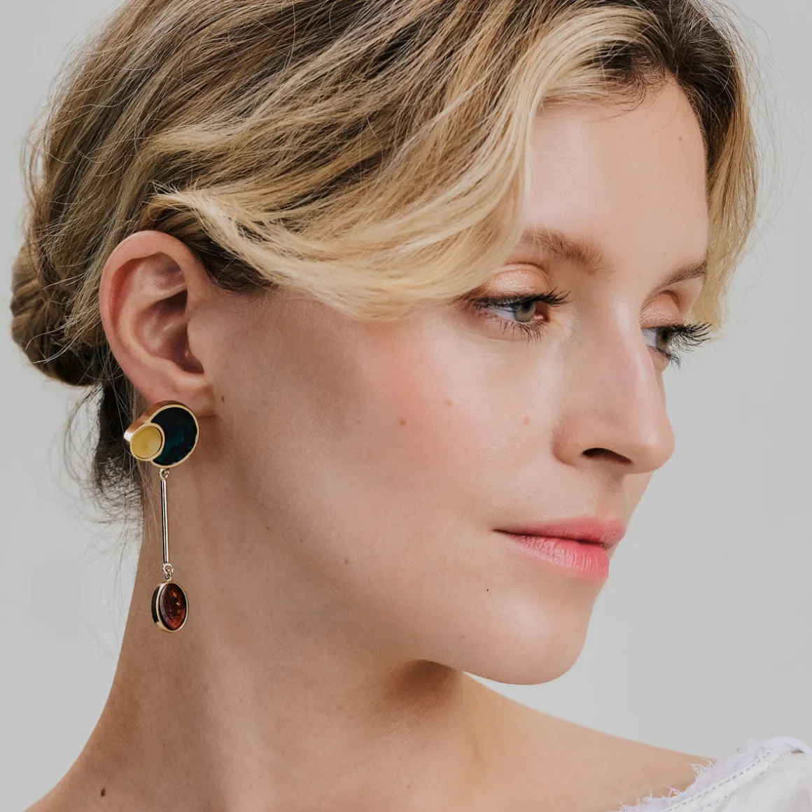 Złote, asymetryczne kolczyki z bursztynem z kolekcji Baltica