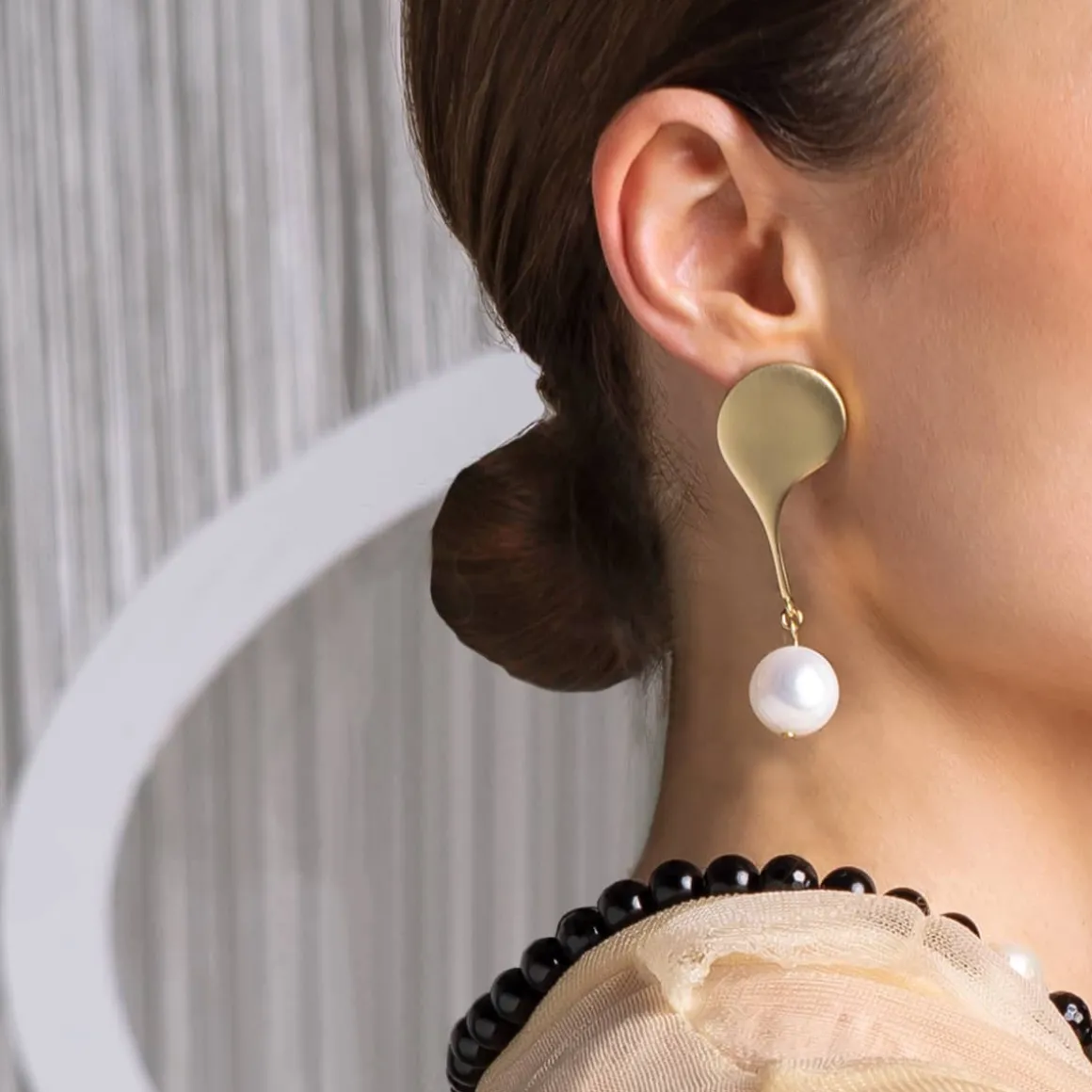 Złote, asymetryczne kolczyki z perłą i onyksem z kolekcji Parer